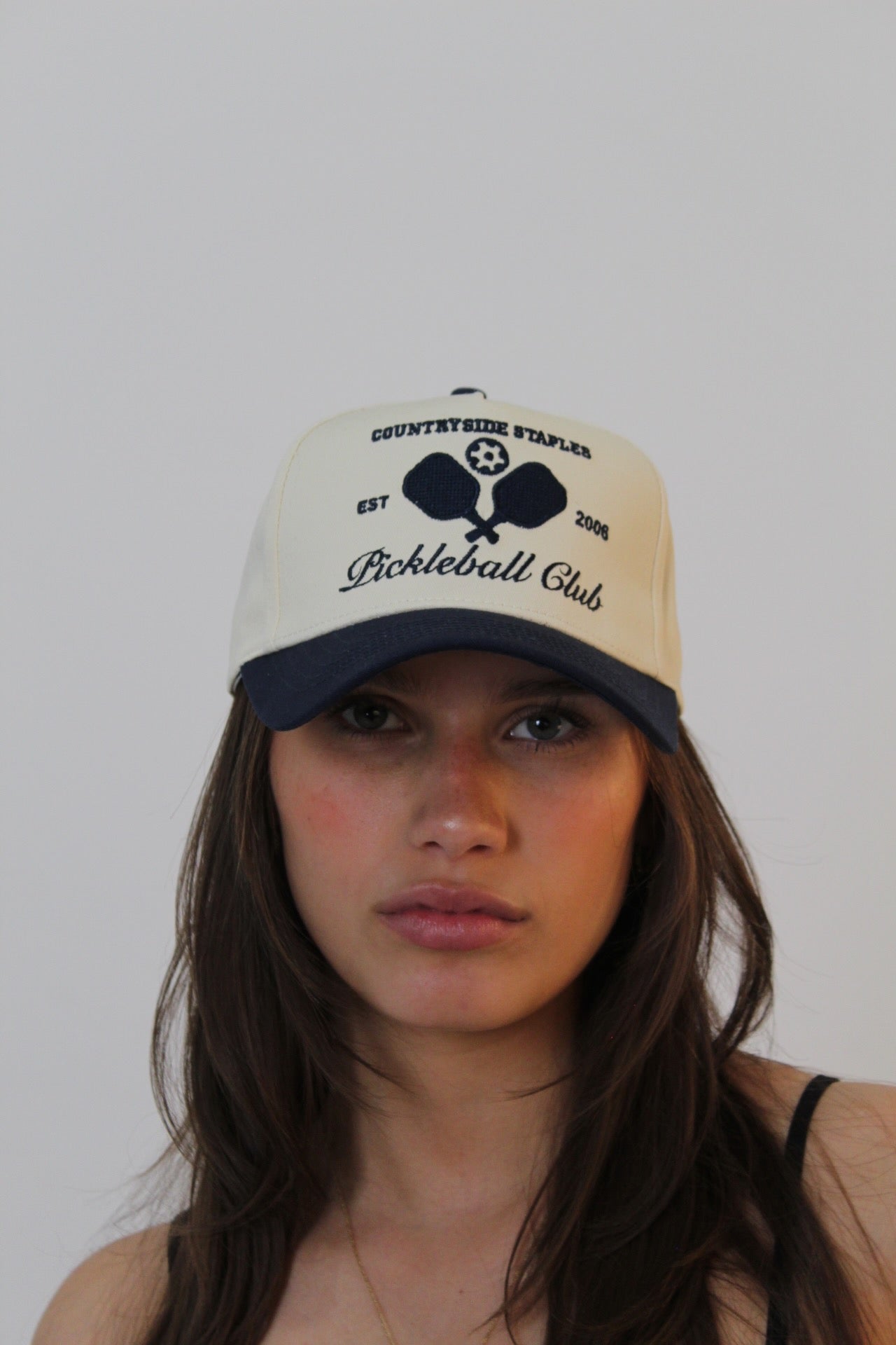 Model wearing Countryside Staples Pickleball Club Hat, front view with logo and crossed pickleball paddles centered on crown