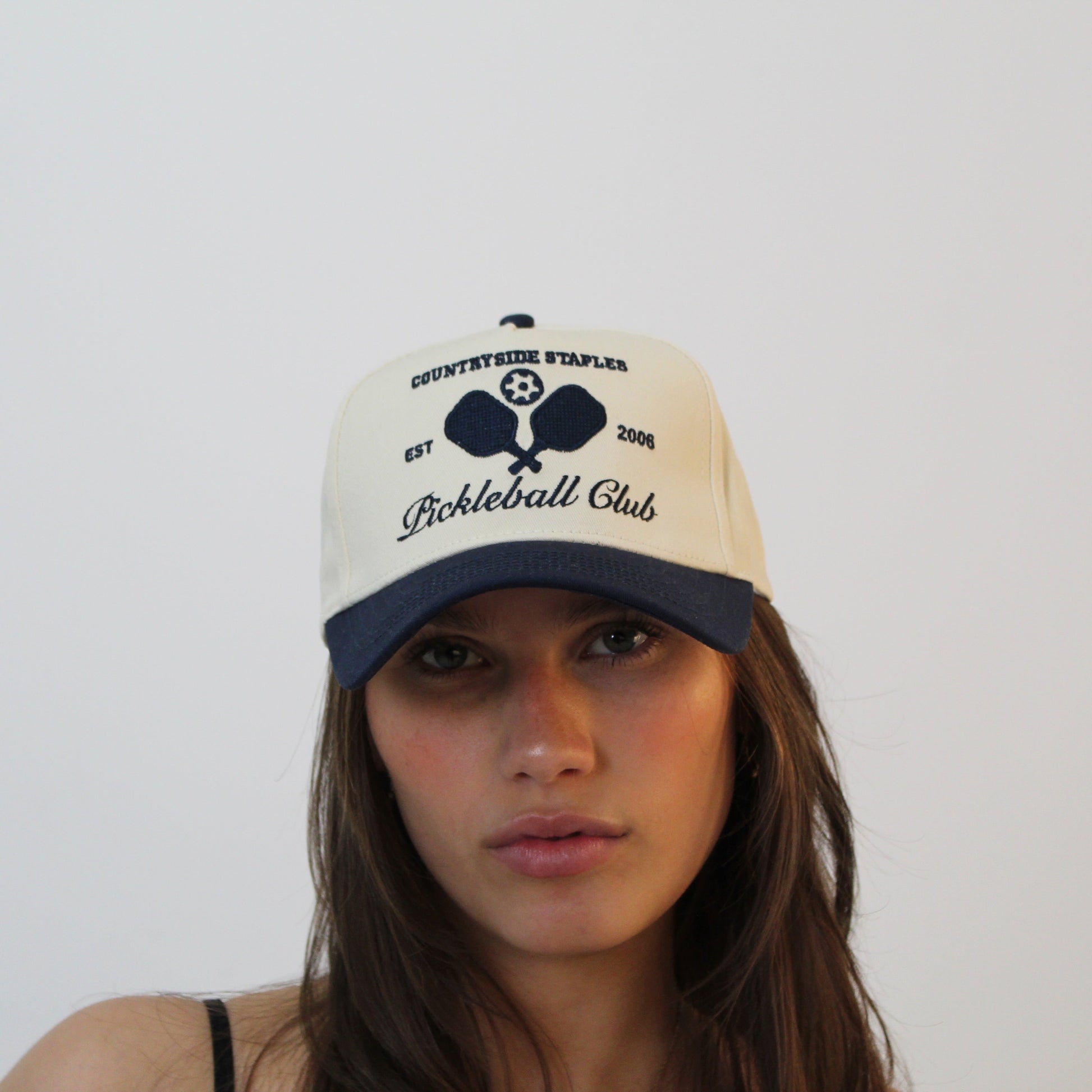 Model wearing Countryside Staples Pickleball Club Hat,  with logo and pickleball paddles centered on crown