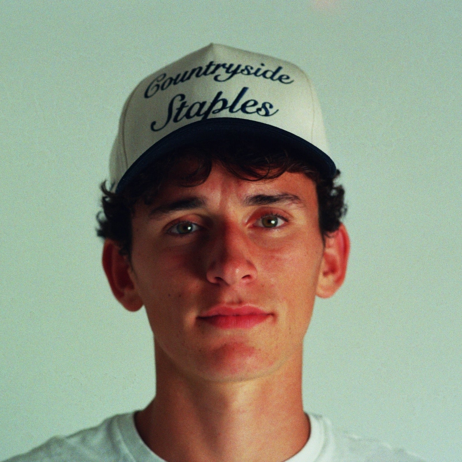Model wearing Signature Navy & Cream Countryside Staples Hat with embroidered logo in film.