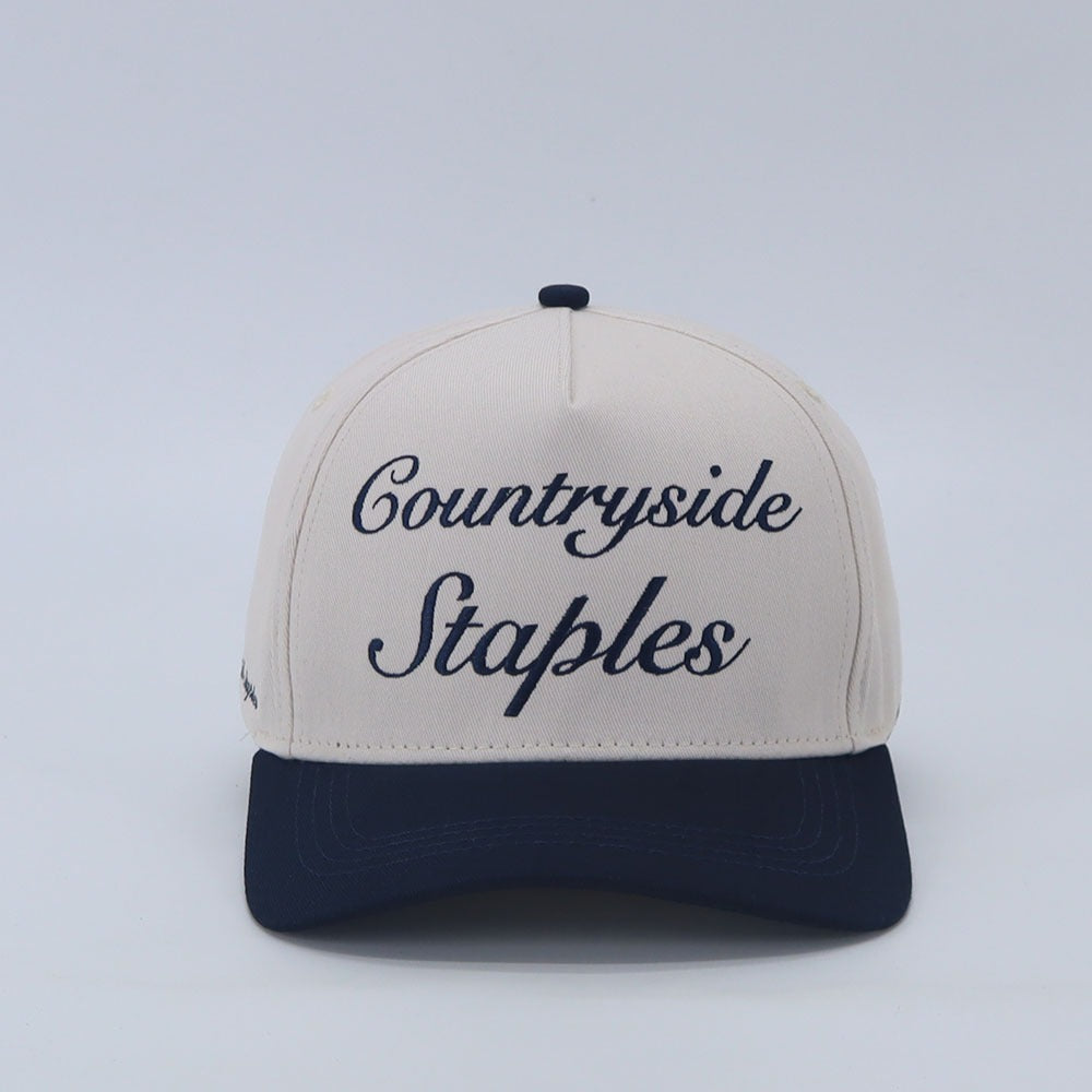Signature Navy & Cream Countryside Staples Hat with embroidered logo laid flat on a white background front view.