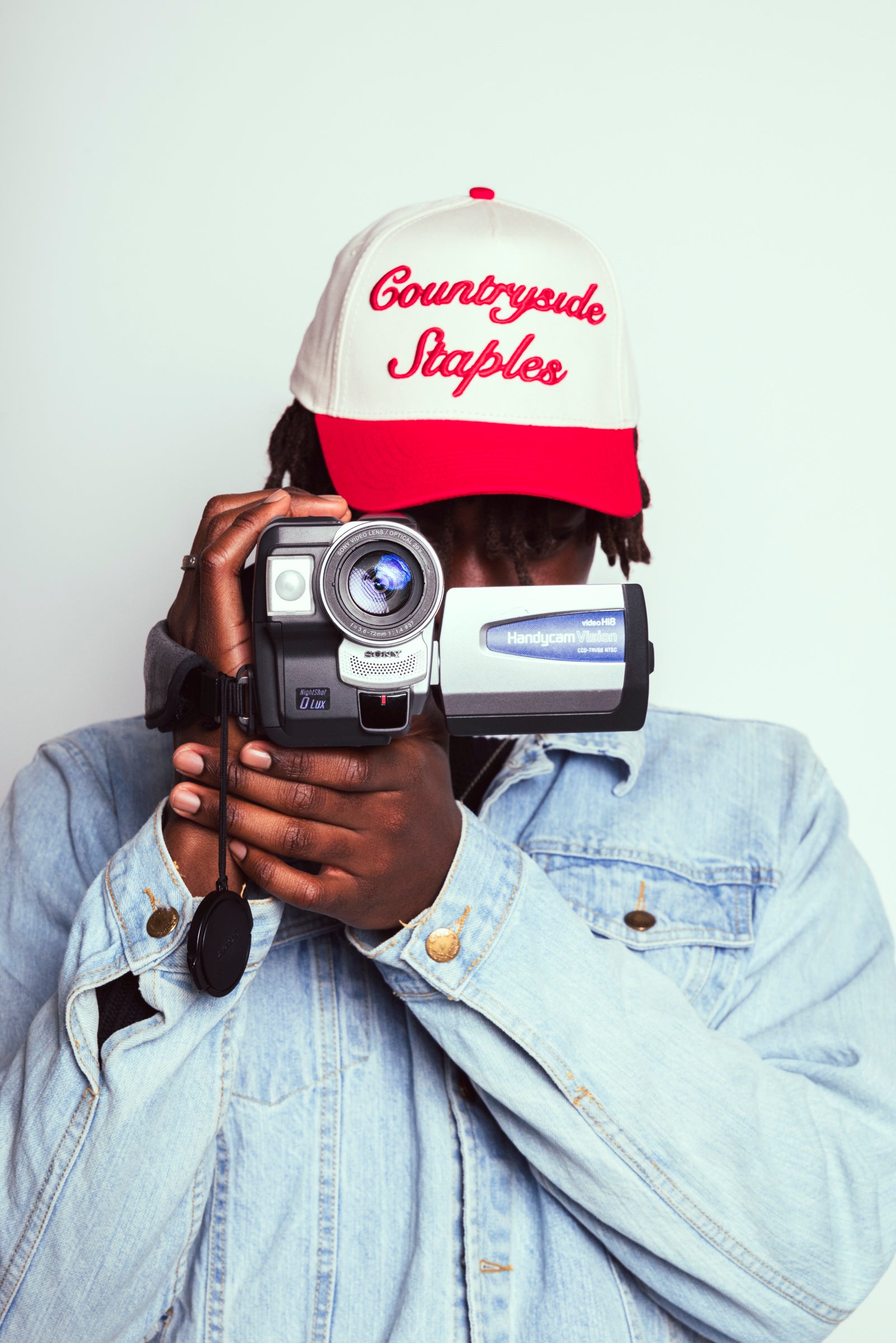 Model wearing Signature Red & Cream Countryside Staples Hat while filming on VHS camera