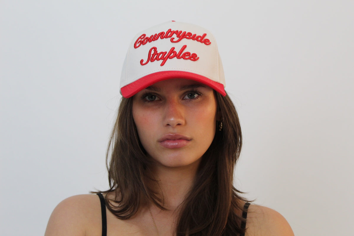Model wearing Signature Red & Cream Countryside Staples Hat front view with 3D embroidered logo