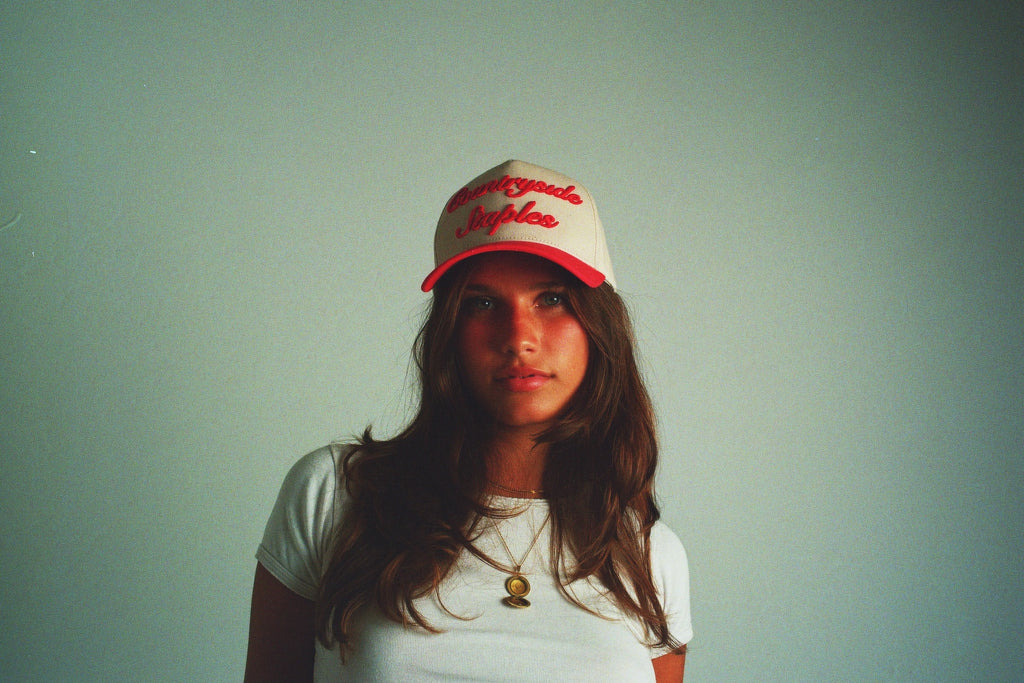 Model wearing Red & Cream Countryside Staples Hat with 3D embroidered logo in film.