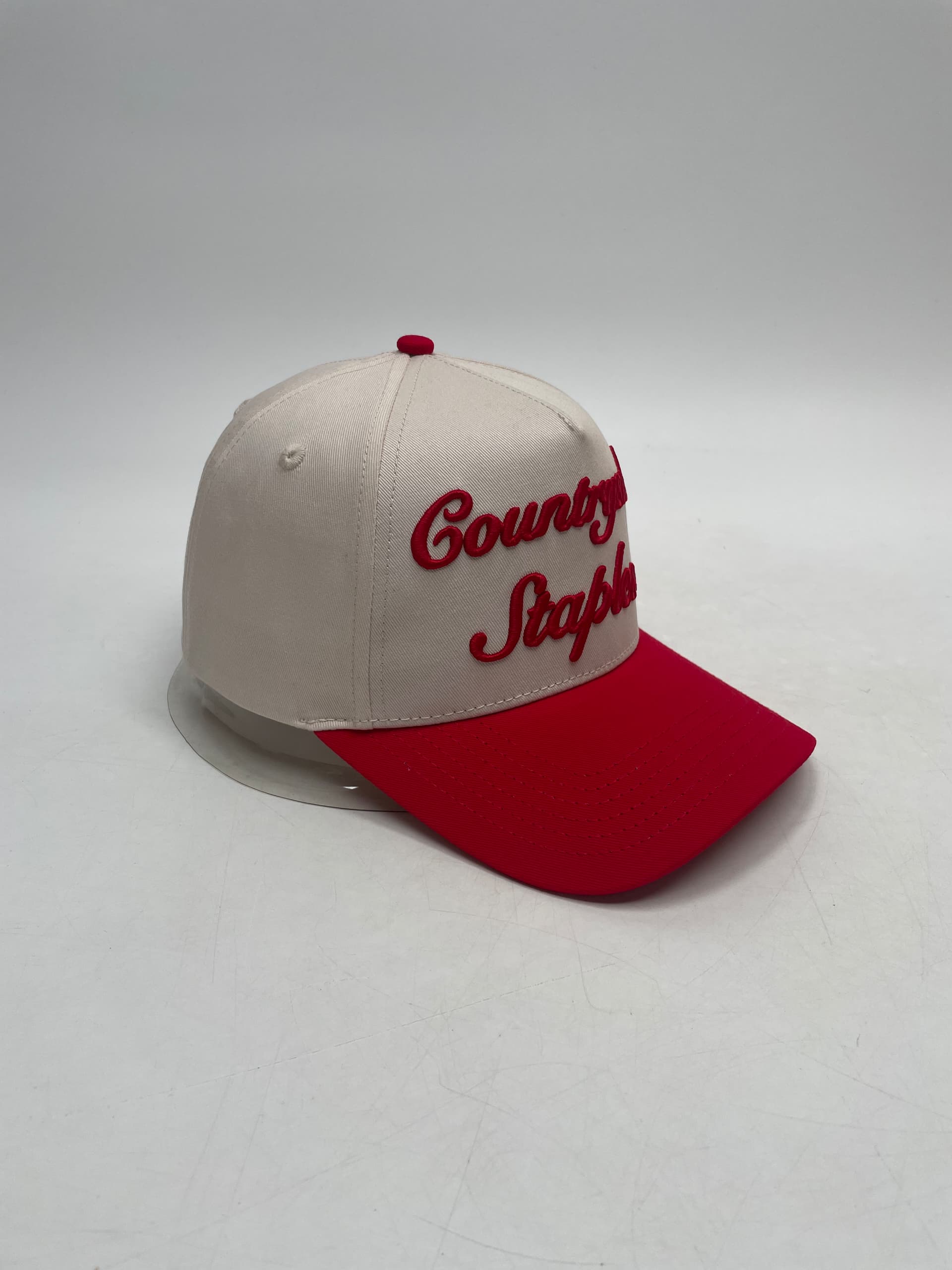 Signature Red & Cream Countryside Staples Hat with 3D embroidered logo laid flat on a white background side view.